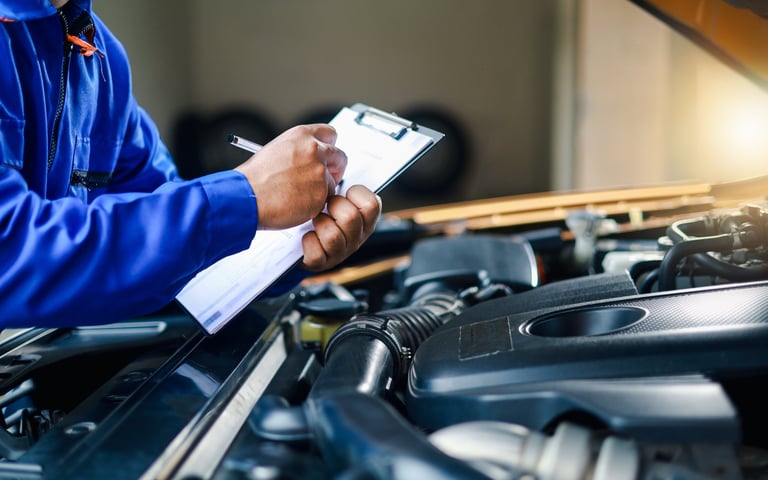 Mechanic checking car with clipboard